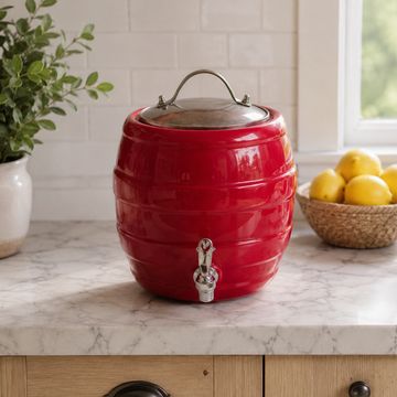 Red ceramic beverage dispenser with a tap on a kitchen counter.