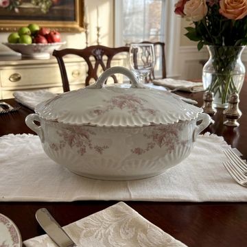 Elegant vintage soup tureen with floral design on a dining table.