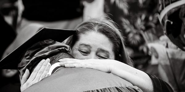A black and white photo of a mother hugging her graduating son