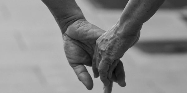 A black and white photo of two people holding hands