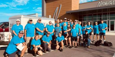 Group of people in matching blue shirts posing outdoors.