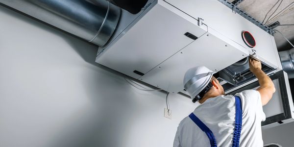 Technician inspecting HVAC system in a building.