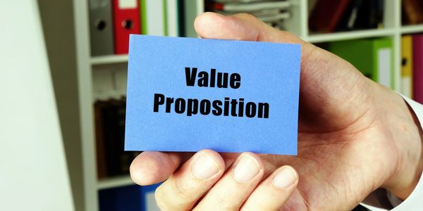 Hand holding a blue card with 'Value Proposition' text.