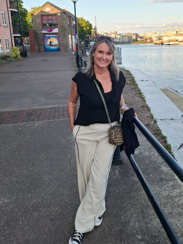 Woman smiling by the waterfront on a sunny day.