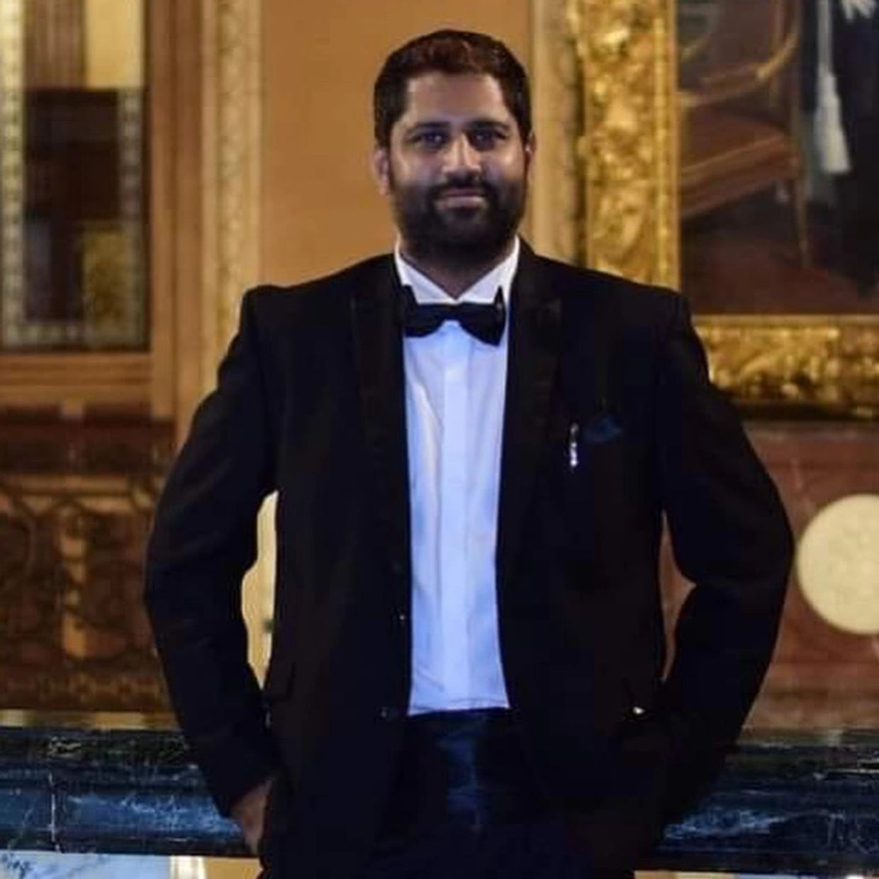 Man in black tuxedo with bow tie indoors.
