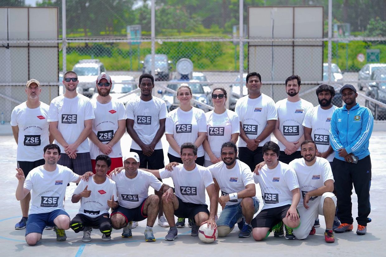 Group photo of a diverse soccer team on an outdoor court.
