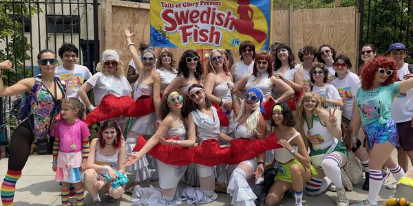 Group of people in colorful outfits posing happily outdoors at a Swedish Fish event.