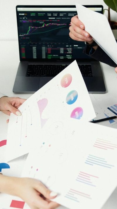 Person reviewing colorful business charts and graphs.