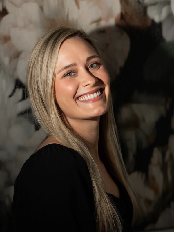 Smiling blonde woman with long hair in black top.