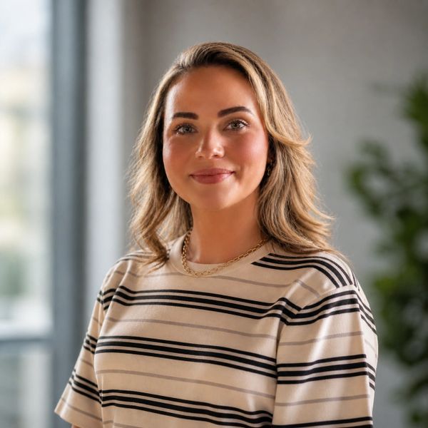 Confident woman in a striped shirt smiling gently indoors.