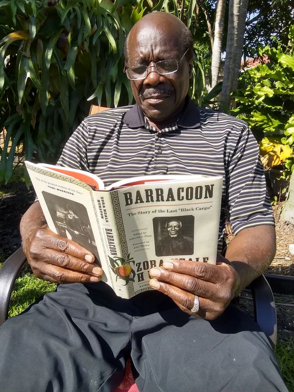 An African American man reading Barracoon by Zora Neale Hurston from Sankofa Essential Books.