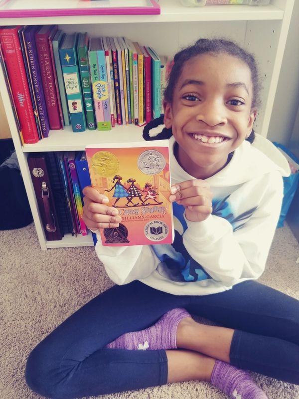 A young girl reading a paperback book by an African American Author from Sankofa Essential Books.