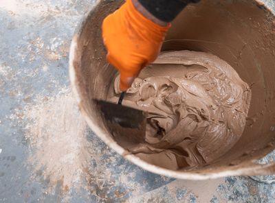Mixing plaster in a bucket with a hand tool