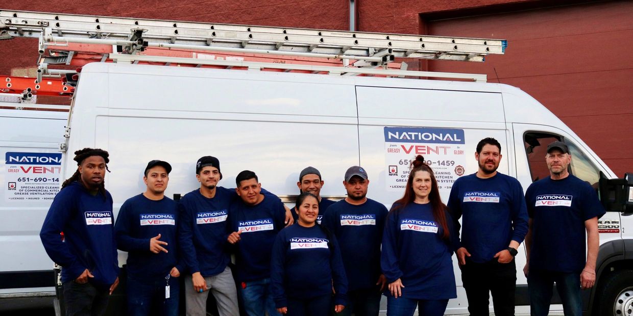 Team of workers in matching National Vent shirts posing in front of company vans.