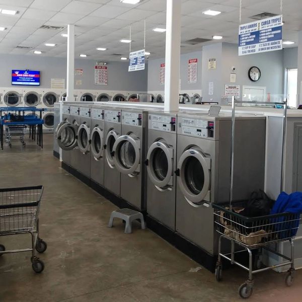 A row of stainless steel washing machines in a laundromat.