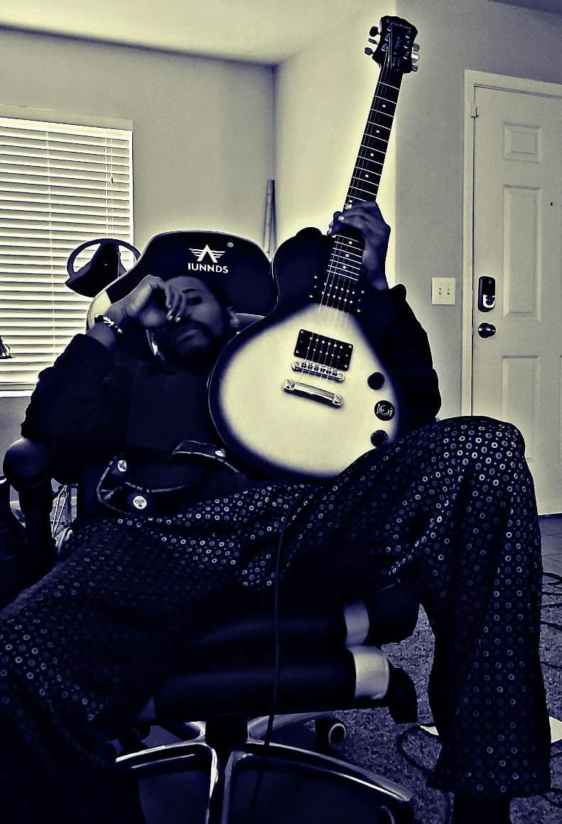 Person relaxing in a chair holding a guitar.