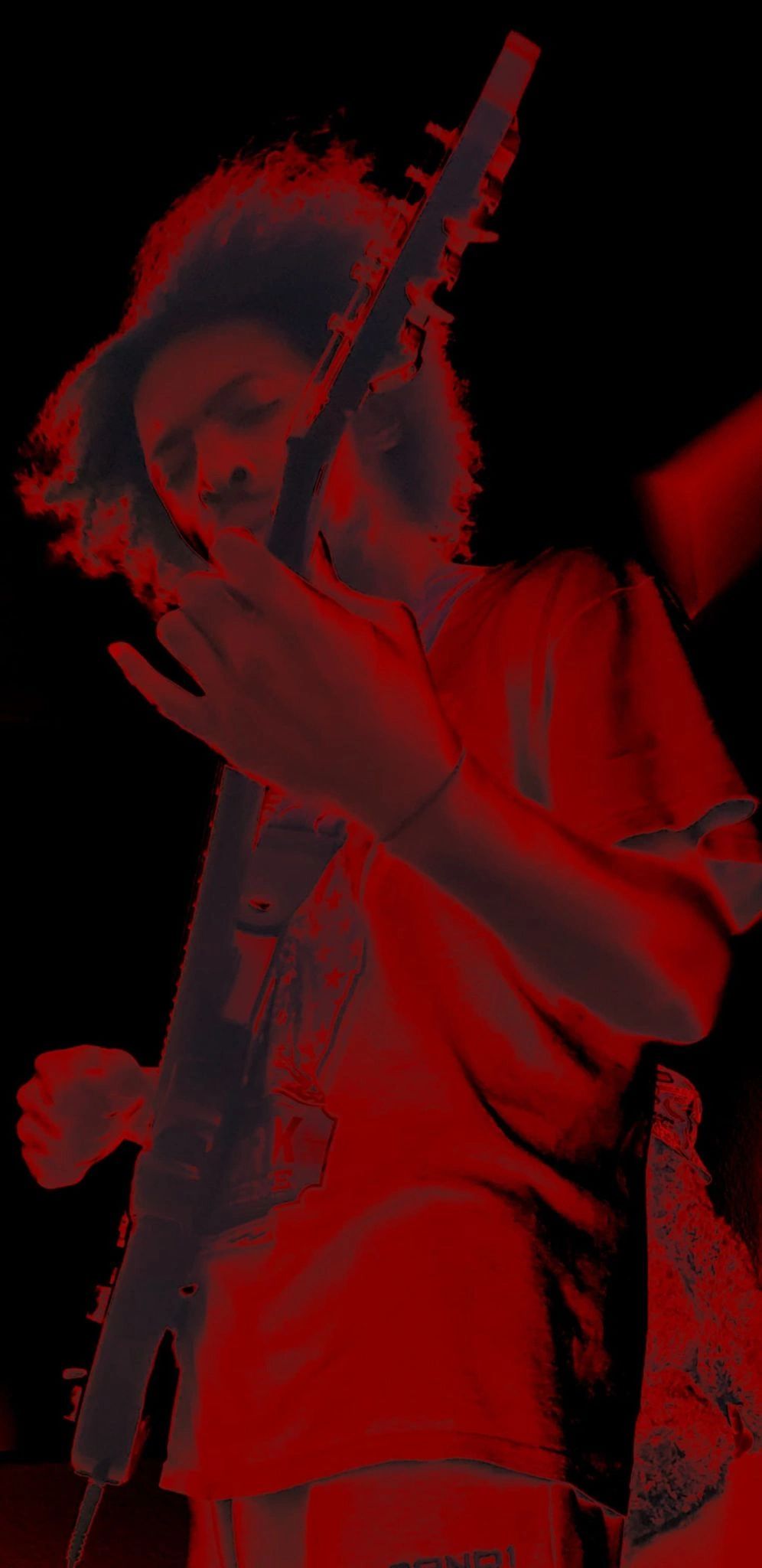 Person playing electric guitar with red filter effect.