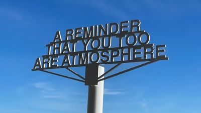 A metal sign reads, 'A REMINDER THAT YOU TOO ARE ATMOSPHERE' against a clear blue sky.