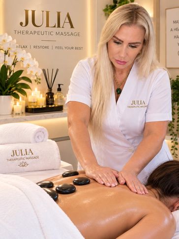 Therapist performing hot stone massage at Julia Therapeutic Massage.