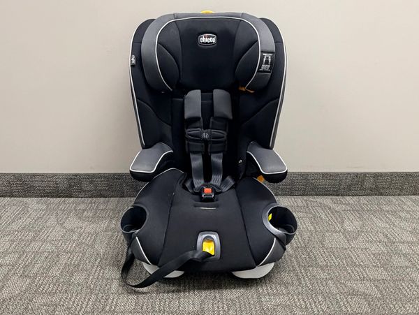 Black Chicco child car seat with cup holders and safety harness.