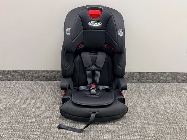 Black Graco child car seat with red accents on a carpeted floor.