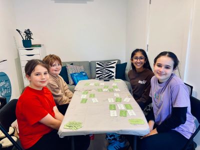 Four kids sitting around a table playing a card game.