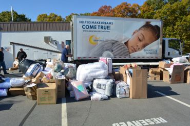 Donation drive with supplies in front of a charity truck.