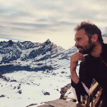 Man enjoying a snowy mountain view at sunset.