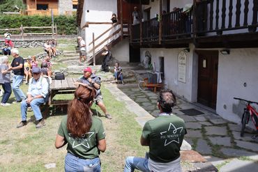 People gather outdoors near a traditional building on a sunny day.