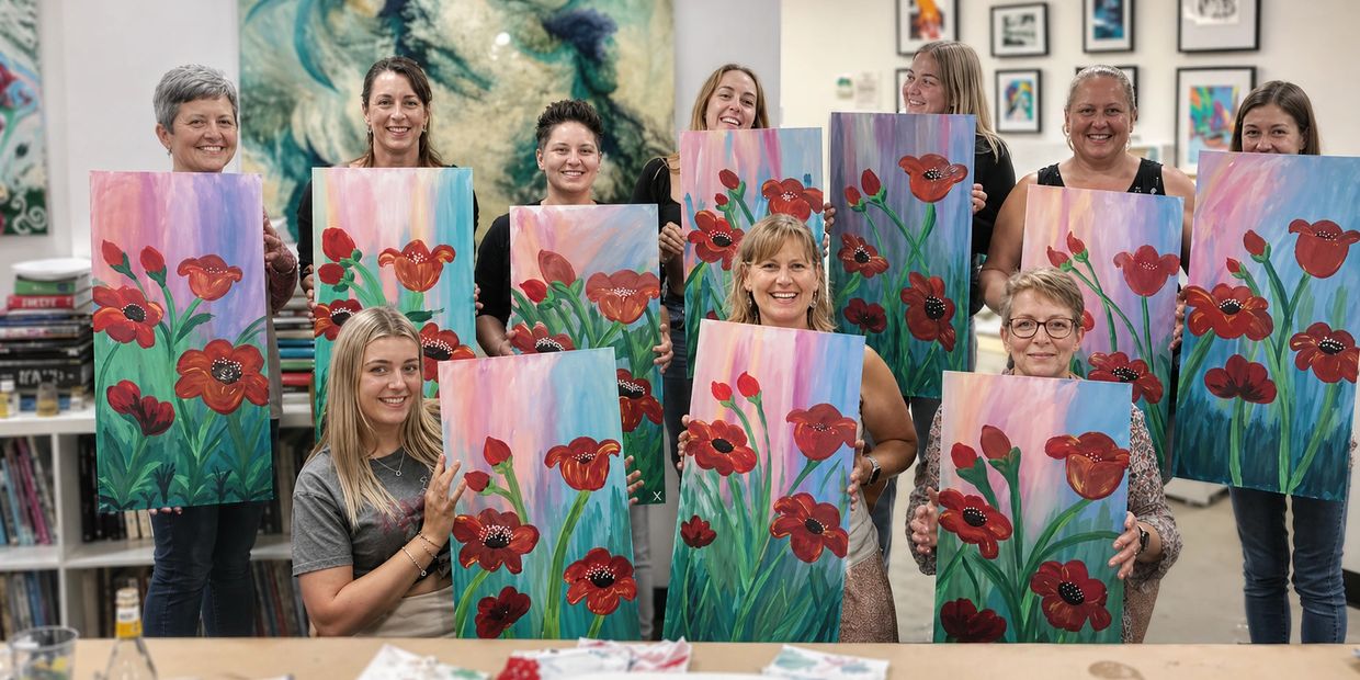Group of women proudly displaying their floral paintings in an art class.