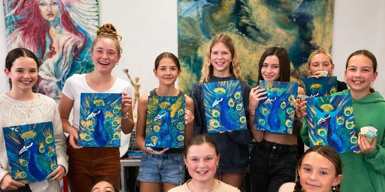 Group of smiling girls holding paintings of peacocks with vibrant blue and yellow colors.