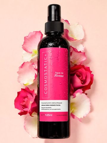 Botella de agua de rosas con flores de rosa alrededor.