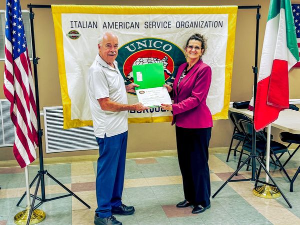 Two people holding a certificate at an Italian American event.