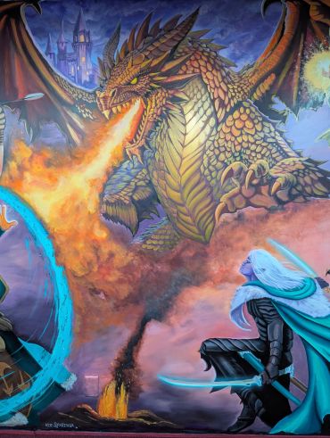 A fierce dragon breathes fire at a warrior with a glowing sword.