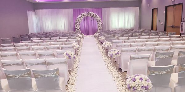 Elegant wedding ceremony setup with white chairs and floral decorations.