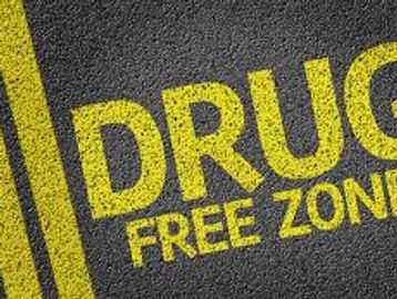 Yellow text on pavement reading 'DRUG FREE ZONE'.