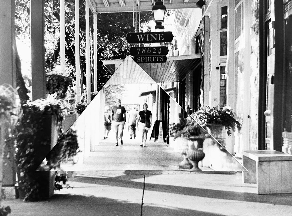 Mirror on sidewalk reflecting people walking.