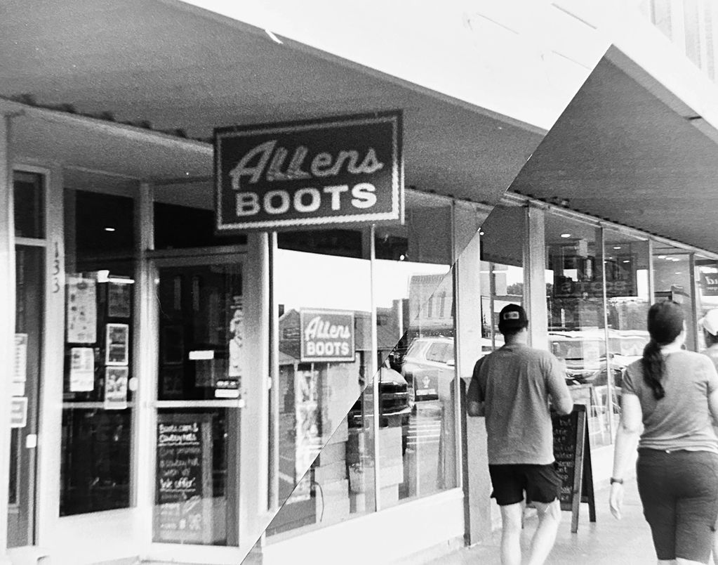 Black and white image of Allen's Boots store with two people walking by.