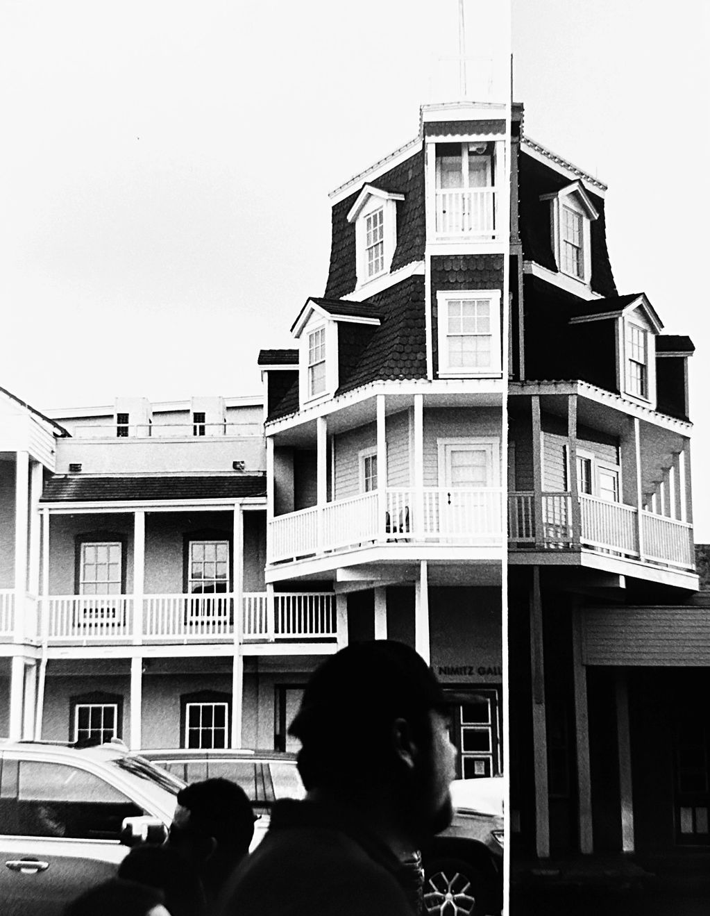 Black and white building split into light and dark halves with silhouettes of people in front.