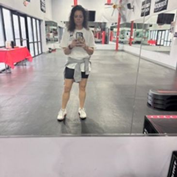 Person taking a gym mirror selfie in workout attire.