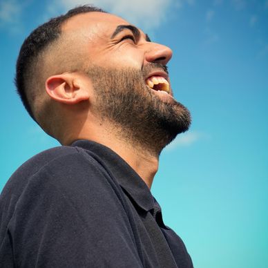 Man laughing joyfully against a clear blue sky.