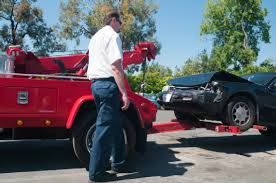 Customer watching as scrap car is winched onto tow truck for removal