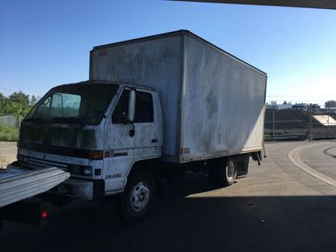  Scrap cube van being towed by a flatbed wrecker in Burnaby
