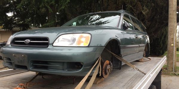 Free car removal service towing a vehicle with missing wheels