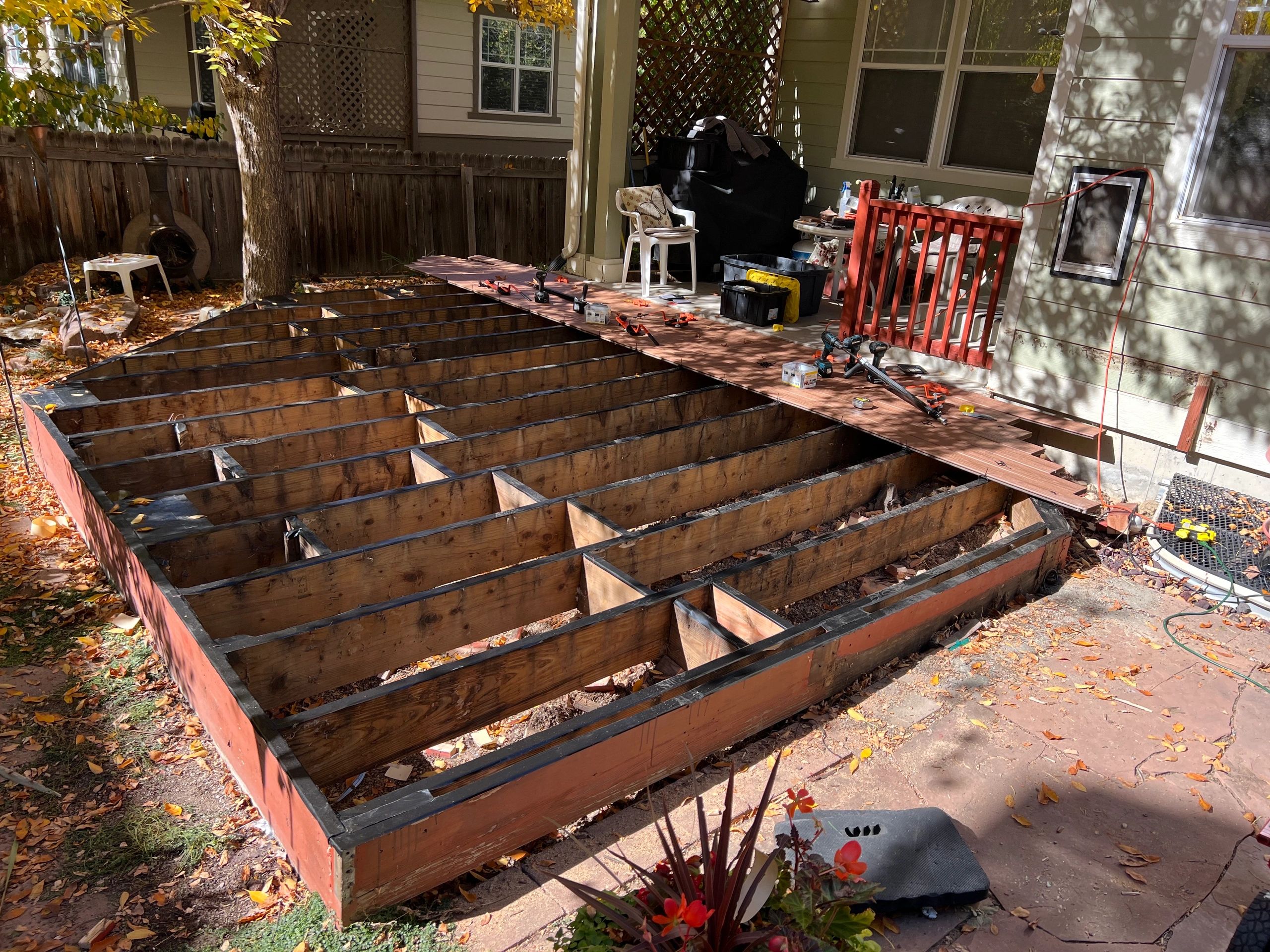 Wooden deck construction in progress with tools and materials scattered around.