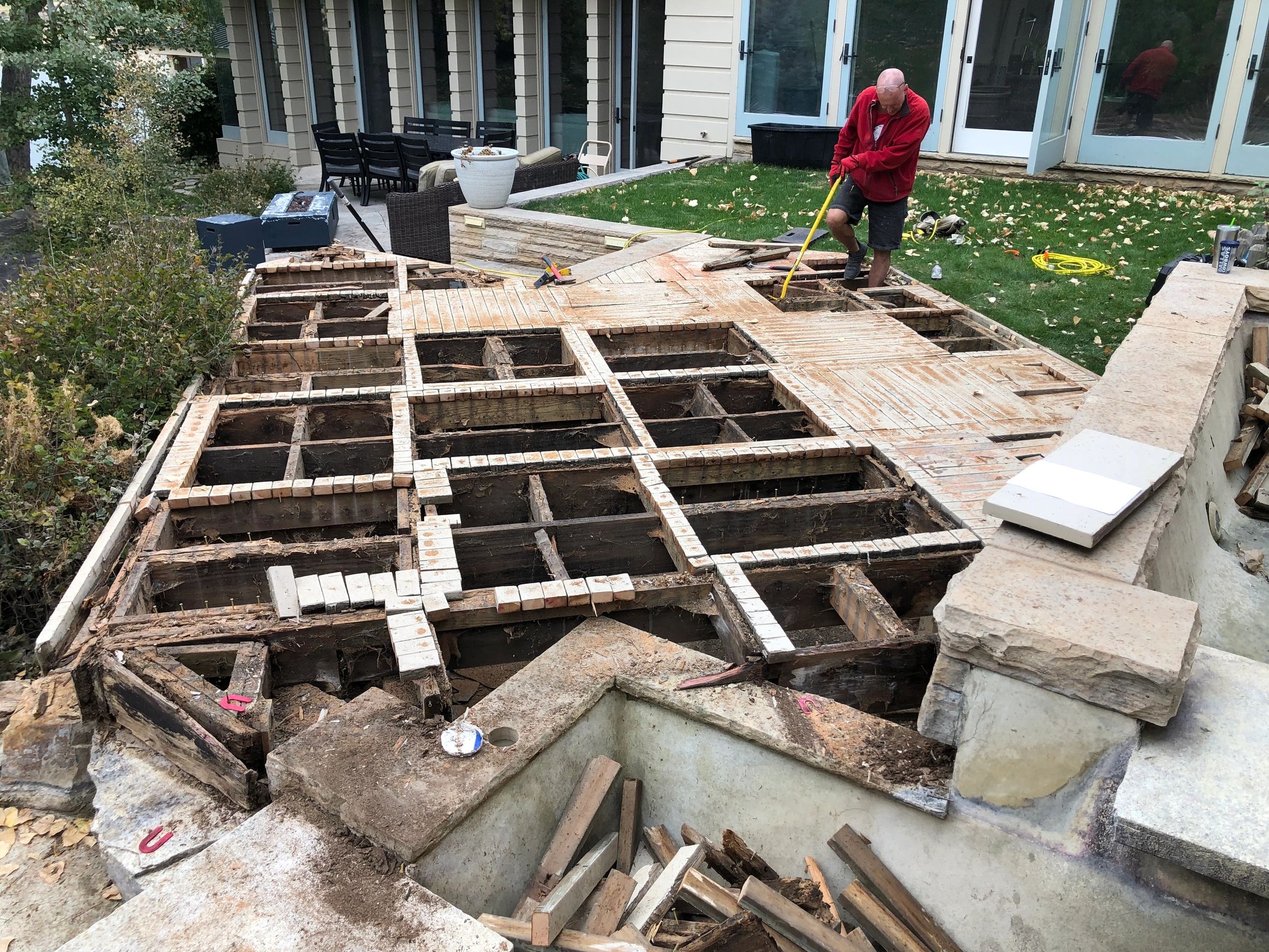 Man working on dismantling a wooden patio deck.