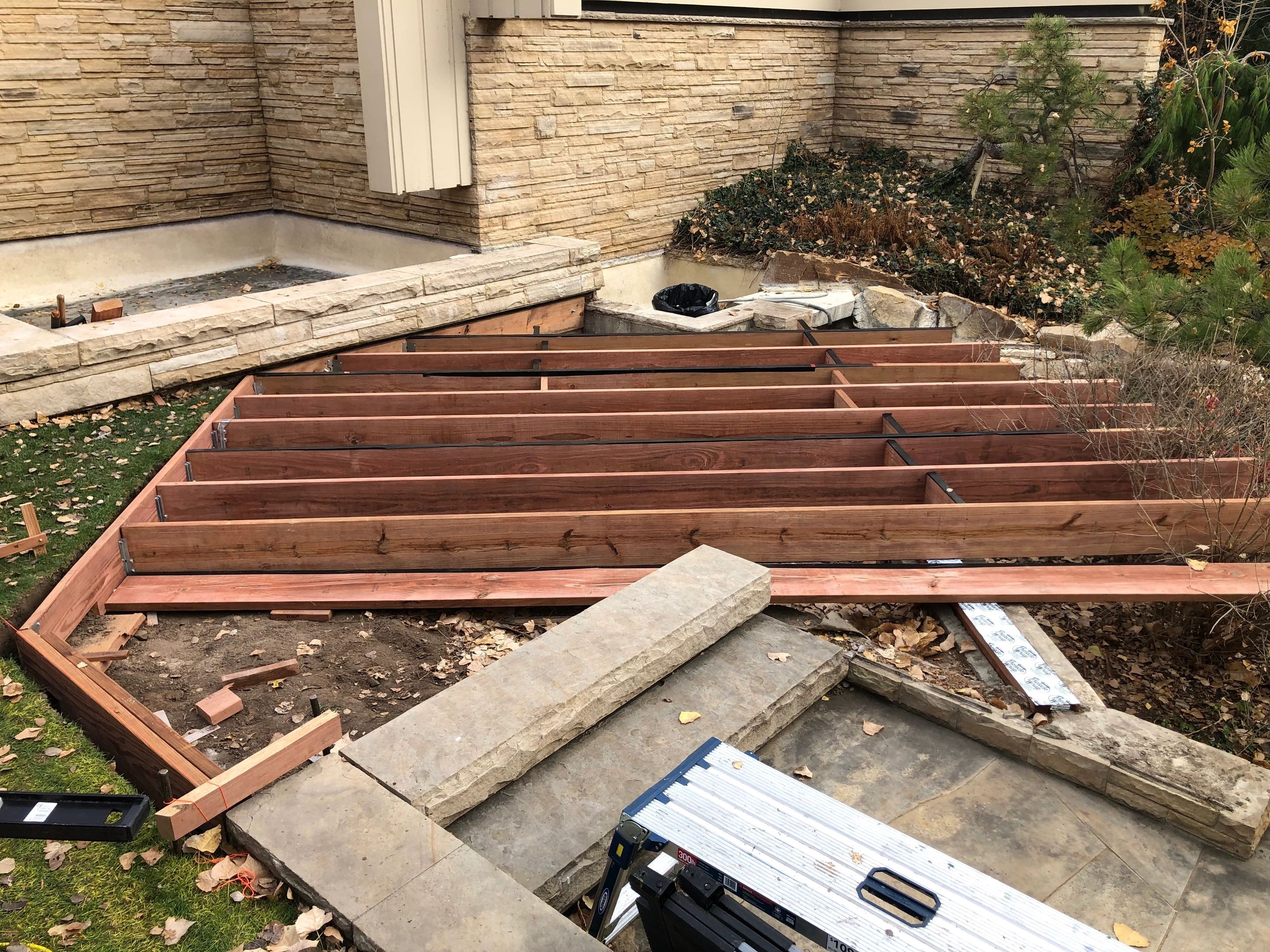 Wooden deck frame construction in a backyard garden.