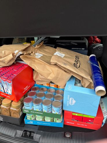 Packed car trunk with groceries and baby wipes.