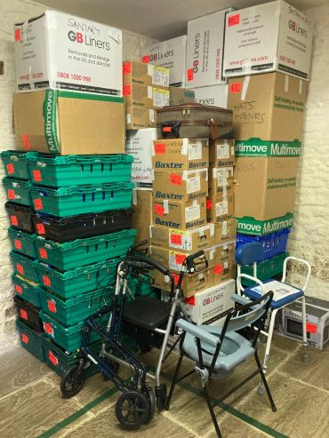 Stacked moving boxes and green crates with mobility aids in a storage room.