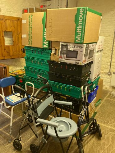 Stacked moving boxes and mobility aids in a room.